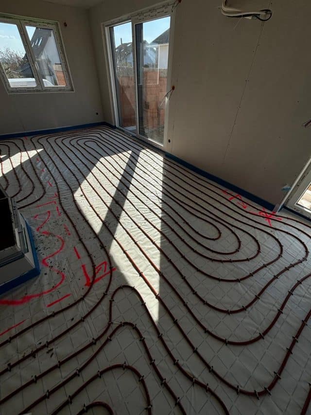 Pose de tubes de plancher chauffant près d’une baie vitrée à Pfettisheim